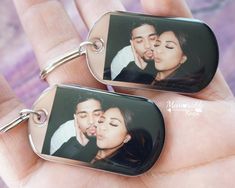 a couple is kissing on their keychains in the palm of someone's hand