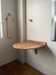 a wooden surfboard mounted to the side of a white wall next to a window