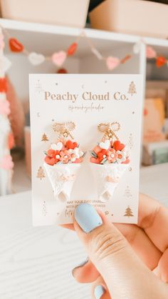 a person holding up a card with two small flowers on it's earring