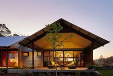 a house that is lit up at night with the sun shining on it's roof