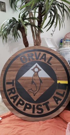 a wooden sign sitting on top of a table next to a potted plant in a room