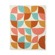 an orange, blue and green quilt with leaves on it's sides in the shape of circles