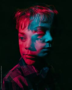 a young boy with red and blue lights on his face, looking at the camera