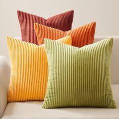 four different colored pillows sitting on top of a couch