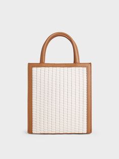 Our woven bag made in a chocolate-beige combination will add a refreshing touch to all your summer looks this season. Contrasted by a beautiful brown trim and a texturally rich body, this bag is versatile, chic and functional. The compact-sized interior ensures ample space for all your daily essentials, while the magnetic closure keeps them secure. On your next resort getaway, we recommend styling it with a floral dress and straw hat. Complete the look with a tie-around platform sandals. Charles And Keith, Circle Handle, Trapeze Bag, Slouchy Tote, Chain Strap Bag, Brown Trim, Charts For Kids, Size Chart For Kids, Charles Keith