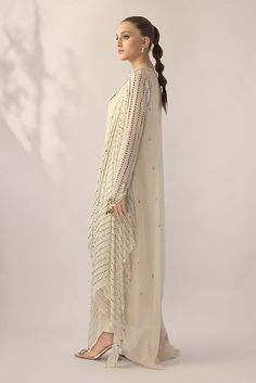 An ivory georgette long shirt with a draped dupatta is handworked with delicate kamdani. The sleeves and neckline are detailed with jewelled floral motifs. An elegant ensemble for any formal event or soiree. Draped Georgette Dress With Sheer Dupatta, Designer Wear Draped Dupatta With Mirror Work, Designer Draped Dupatta With Mirror Work, Georgette Dresses With Resham Embroidery And Cape Sleeves, Designer Mirror Work Draped Dupatta, Elegant Off White Kurta With Dupatta, Elegant Draped Designer Dresses, Off White Dupatta With Mirror Work, Traditional Drape, Off White Dupatta With Mirror Work