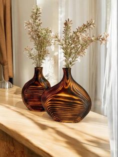 two vases with flowers in them sitting on a table