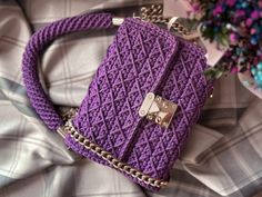 a purple purse sitting on top of a bed