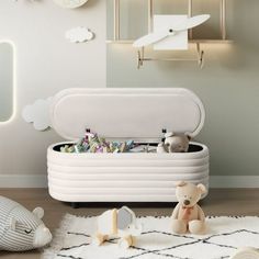 a white toy chest sitting on top of a wooden floor next to stuffed animals and toys