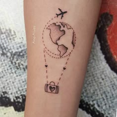 a small tattoo on the arm of a woman with an airplane flying over the earth