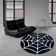 a black chair sitting next to a spider web rug on top of a white floor