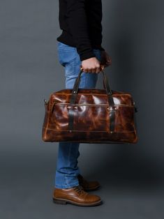 Here is the perfect blend of sophistication and style with our unique leather duffle bag in a rich, textured saddle tan, accented by sleek black handles. The full-grain buffalo leather adds to the endurance yes well as the charm of the duffle bag. Best for short trips and routine journeys. Elevate your travel game with this distinctive accessory today! Salient Features Made of full-grain premium buffalo leather Pure brass hardware with bottom studs to protect the bag Adjustable leather shoulder Rugged Brown Bag With Luggage Sleeve, Leather Cognac Satchel With Luggage Sleeve, Classic Brown Travel Bag With Leather Trim, Vintage Brown Leather Bag With Luggage Sleeve, Brown Leather Satchel With Luggage Sleeve, Rugged Leather Rectangular Duffle Bag, Brown Travel Bag With Leather Trim And Double Handle, Brown Leather Trim Weekender Bag For Business, Brown Leather-backed Tote Travel Bag