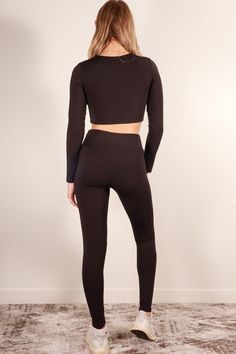 A polyamide elastane set featuring a long sleeve crop top, high waist leggings, and 4 way stretch from Capella Apparel Activewear Style Number: ATP71016 Fabric Details: 80% Polyamide, 20% Elastane Model is 5'9" and is wearing a Small Top - Bust: 13", Body Length: 14", Sleeve Length: 23" Bottom - Inseam: 27", Waist: 11.75", Total Length: 36.75" Elastane Long Sleeve Activewear, High Waist Stretch Black Crop Top, Winter Stretch Elastane Activewear, Black Compressive Cropped Activewear, Sporty Fitted Cropped Bottoms, Tight Long Sleeve Winter Activewear, Compression Long Sleeve Activewear, Compression Long Sleeve Activewear In Elastane, Fitted Elastane Activewear For Fall