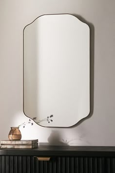 a mirror sitting on top of a dresser next to a vase