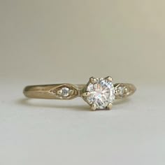 a close up of a diamond ring on a white surface with a light colored background