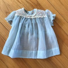 "Darling Delicate Vintage 1950s Sheer Blue Baby Apron Dress With Delicate Lace Trim! SO Cute MEASUREMENTS Please compare measurements to those of clothes your little one already wears to ensure best fit.  measurements taken with the garment laying flat and then doubled S2S: 8\" Seeve: 3 1/2\" Armpit to Armpit: 28\" L: 13 3/4\" Label: None  Material: Most likely Polyester  Condition: Very Good. It does have a line like stain in the fornt - refer to last photo. Please review the photos carefully. We examine each item carefully and do our best to note imperfections. Please understand that vintage items are not new. All items are pre-loved and sold AS-IS. Feel free to reach out with any questions. Thanks for looking!" Blue Vintage Dress With Lace Trim, Vintage Blue Dress With Lace Trim, Vintage Light Blue Dress For Daywear, Light Blue Vintage Daywear Dress, Vintage Light Blue Daywear Dress, Vintage Blue Dress For Daywear, Vintage Blue Daywear Dress, Vintage Blue Dresses For Daywear, Blue Baby Dress