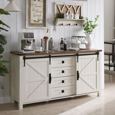 a kitchen with white cabinets and wooden counter tops, along with potted plants on the wall