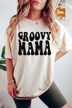 "The Groovy Mama Retro Comfort Colors Shirt is a stylish and comfortable shirt that is perfect for any mom who wants to show off her retro style. The shirt is made from 100% ringspun cotton, which is soft and breathable, making it perfect for everyday wear. It features a classic fit, ribbed collar, and double-needle stitching, ensuring it will last for years to come. The shirt also has a vintage-inspired design with the word \"Mama\" in bold letters on the front, making it a great gift for any mom. Product Features: 100% ringspun cotton Classic fit Ribbed collar Double-needle stitching Vintage-inspired design Available in multiple colors and sizes Product Benefits: Soft and breathable fabric for all-day comfort Durable construction ensures long-lasting wear Stylish design allows moms to sh Groovy Relaxed Fit Tops With Letter Print, Groovy Cotton Tops With Relaxed Fit, White Groovy Short Sleeve Tops, Groovy White Short Sleeve Tops, White Short Sleeve Groovy Tops, Groovy Relaxed Fit Crew Neck Top, Groovy Cotton Tops With Graphic Print, Groovy Long Sleeve Cotton Tops, Groovy Cotton Top With Graphic Print