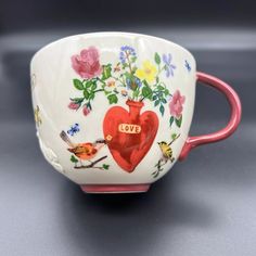 a cup with flowers and birds painted on the inside is sitting on a gray surface