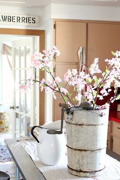 a vase with pink flowers in it sitting on a table next to a white pitcher