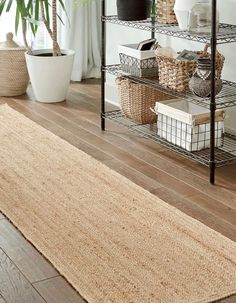 an area rug is on the floor in front of a shelf with baskets and plants