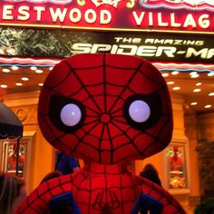 a close up of a stuffed spider man in front of a building with a sign