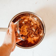 a person is holding a glass bowl with food in it on a white table top