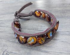 Handcrafted glass bead and leather bracelet. Beads are in a single layer sewn into the leather wrap, ending into a loop and tie. The bracelet is 8 inches long (not including the tie ends). Beaded Leather Wraps, Beaded Wrap Bracelets, Bracelet Leather, Beaded Wraps, Bracelet Beaded, Bead Leather, Leather Wrap Bracelet, Leather Wraps, Glass Bead