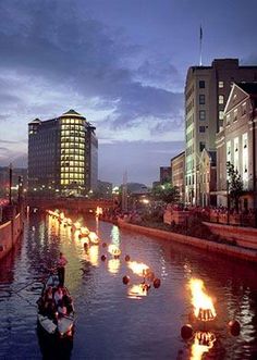 the boats are traveling down the river in the city at night with bright lights on them