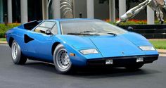 a blue sports car parked in front of a building