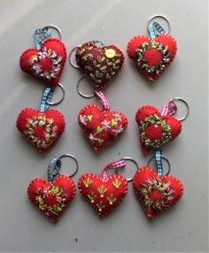 several red heart shaped ornaments hanging from hooks on a white counter top with blue and pink ribbon