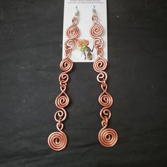 a pair of earrings is shown on a black surface with a card attached to it