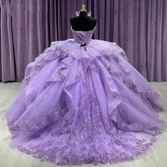 a purple ball gown is displayed on a mannequinl stand in front of curtains