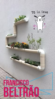 two white shelves with plants and flowers in them on the side of a building that says tes in love