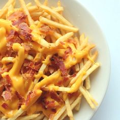 a white plate topped with cheesy fries covered in bacon and melted cheese on top