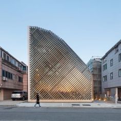 a large triangular shaped building sitting on the side of a road next to tall buildings