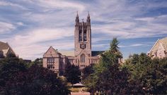 a large building with a clock on it's face surrounded by trees and bushes