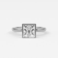 Princess cut diamonds exude modern elegance when set in a bezel setting. This setting surrounds the diamond with a sleek metal rim, securing it firmly while emphasizing its square shape and dazzling facets. The bezel setting not only protects the princess cut diamond from everyday wear but also enhances its brilliance by minimizing distractions and focusing attention on its clean lines and geometric precision. Perfect for those who appreciate a blend of contemporary style and practical design in their jewelry, princess cut diamonds in a bezel setting showcase a sophisticated allure that is both refined and durable. Ring shown is 2 ct diamond. Formal Radiant Cut Rings With Bezel Setting, White Gold Asscher Cut Ring With Bezel Setting, Asscher Cut Diamond Ring With Bezel Setting, White Gold Rings With Bezel Setting, Asscher Cut, Timeless Asscher Cut Diamond Ring With Bezel Setting, Luxury Radiant Cut Diamond Ring With Bezel Setting, Silver Asscher Cut Diamond Ring With Bezel Setting, Modern Princess Cut Jewelry With Vvs Clarity, Formal Asscher Cut Ring With Bezel Setting