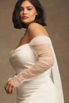 a woman in a white wedding dress and veil posing for the camera with her hands on her hips