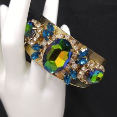 *Description: This is a gorgeous watermelon rhinestone crystal bracelet on a golden brass cuff which glitters and sparkles in the light. The vintage rhinestones are secured on a golden brass cuff and the reflective cuff adds additional sparkle to the bracelet. There is one large watermelon rhinestone in the center, surrounded by clear rhinestones and sapphire blue marquise cut rhinestones. On each side of the center stone are two more watermelon rhinestones, a little smaller in size, one on each Formal Earrings, Brass Cuff Bracelet, Book Pieces, Brass Cuff, Blue Rhinestones, Sapphire Blue, Crystal Bracelet, Vintage Bracelets, Marquise Cut