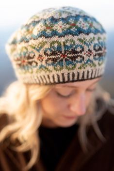 a woman is looking down at her cell phone while wearing a knitted beanie