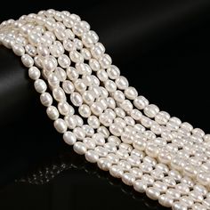 three strands of white pearls on a black surface