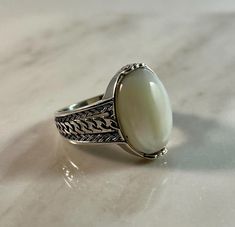 Enhance your style with this meticulously handcrafted 925 sterling silver men's ring. Featuring a smooth, oval-shaped mother-of-pearl stone set in a beautifully detailed band, this ring evokes a vintage aesthetic with intricate and elegant patterns. It adds a touch of timeless sophistication to any outfit and makes a perfect gift for those who appreciate classic jewelry with a modern twist. Crafted from high-quality 925 sterling silver, this ring is both durable and comfortable, making it ideal Pearl Ring For Men, Pearl Stone, Sterling Silver Mens Rings, Ring Antique, Mens Silver Rings, Classic Jewelry, Men's Ring, Vintage Aesthetic, Silver Man