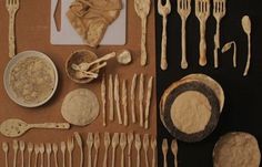 an assortment of utensils and spoons are displayed on a brown tablecloth