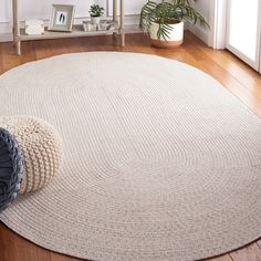 a round rug on the floor next to a potted plant in a living room