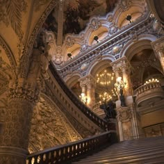 an ornate staircase with chandeliers and paintings on the walls