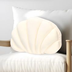 a white pillow sitting on top of a chair next to a wooden armrest and cushion