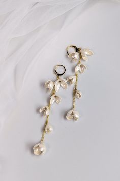 These elegant and delicate ~ J A S M I N E ~ bridal earrings are handcrafted with attention to detail. The cascading design features clusters of white clay pearl flowers, adding a touch of romance and femininity to your special day.  The gold-plated hooks and chain complete the look with a touch of sophistication. Perfect for a spring or summer wedding, these earrings are sure to complement any bridal gown. Earrings measurements: Length: approx 9.7cm (3.8") Matching Items:   See Other  CARING FOR COLD PORCELAIN JEWELLERY  * Handle gently  * Store in a cool, dry place  * Use soft pouches or boxes  * Avoid harsh chemicals and water  * Repair small cracks with clay  * Keep away from perfumes and lotions  * Remove before activities  * Test cleaning methods first Enjoy your beautiful cold porce Clay Bridal Earrings, Gown Earrings, Cold Porcelain Jewelry, Porcelain Jewellery, Wedding Flower Jewelry, Jasmine Bridal, Pearl Flowers, Long Flowers, Bride Earrings