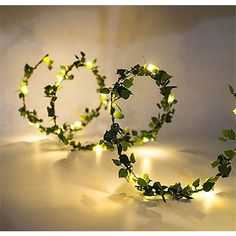 two wreaths made out of green leaves and fairy lights