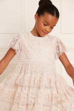 Description and Details The Angelica Lace KIDS in Cream. This elegant dress is designed with intricate embroidery, inspired by Victorian lace trims. Tiered frills add a playful and charming quality to this timeless design. The ultimate addition to your little one's wardrobe. - Tulle decorated all-over with tonal embroidery - 100% Polyester - Fully lined - Grosgrain ribbon trim around waistline - Tulle frill detail around waistline - Concealed zip at centre back - Made in India Care Advice - Deli Elegant Lace Dress With Ruffles For Dress-up, Party Dress With Flutter Sleeves And Lace Trim, Short Sleeve Ruffled Dress For Confirmation, Lace Dress With Ruffles And Flutter Sleeves, Baptism Dress With Flutter Sleeves And Ruffles, Spring Confirmation Lace Dress, Cream Dress With Ruffles For First Communion, First Communion Spring Dress With Lace Trim, Spring First Communion Dress With Lace Patchwork